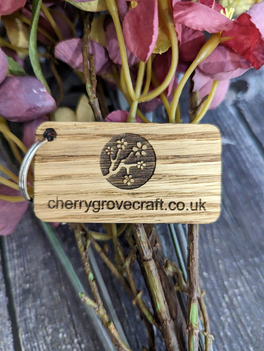 Double-sided 65x35mm keyring close-up — engraved logo on oak