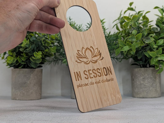 In Session bamboo door hanger hanging on door handle — lotus motif, single-sided, indoor use