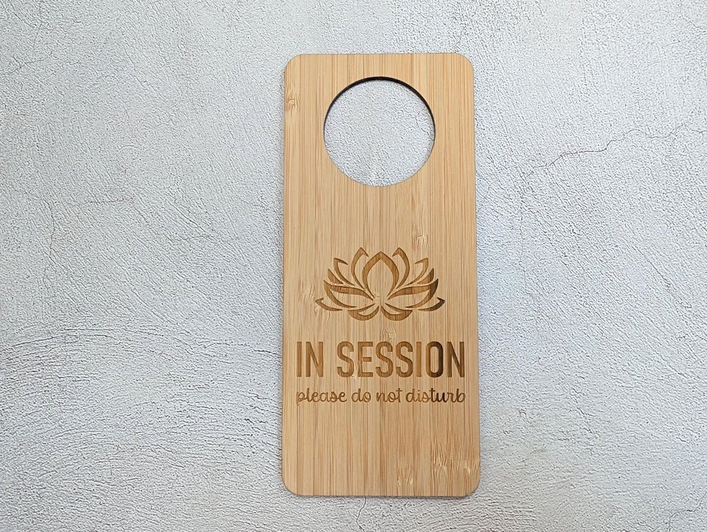 Oak and bamboo In Session door hangers shown together — grain and tone comparison, lotus design