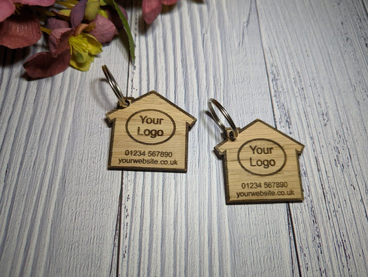 Two house-shaped oak keyrings engraved with estate agent branding
