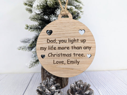 Personalised oak Christmas bauble engraved with a short message inside a cut-out heart border, hung on jute string