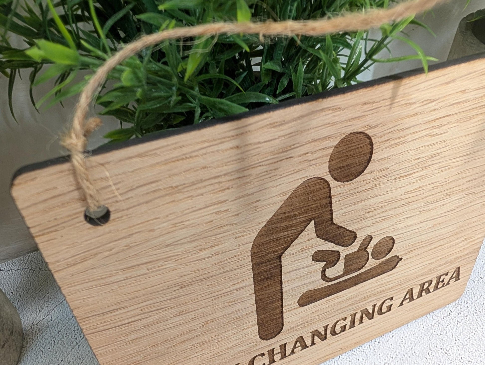 Baby changing sign close-up — laser-engraved text and jute string hanging loop
