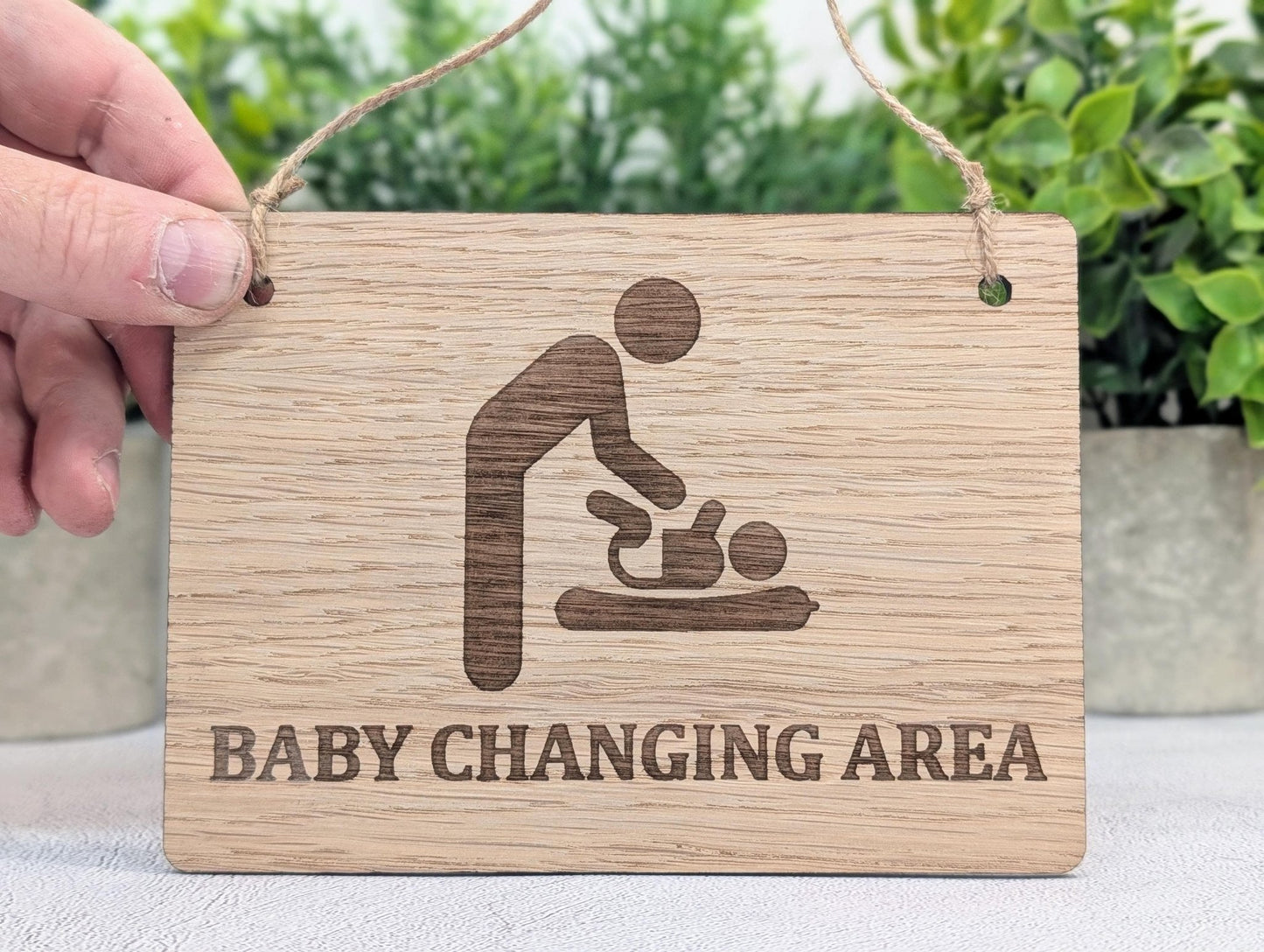 Baby changing area sign — oak veneered MDF, hung on wall with jute string