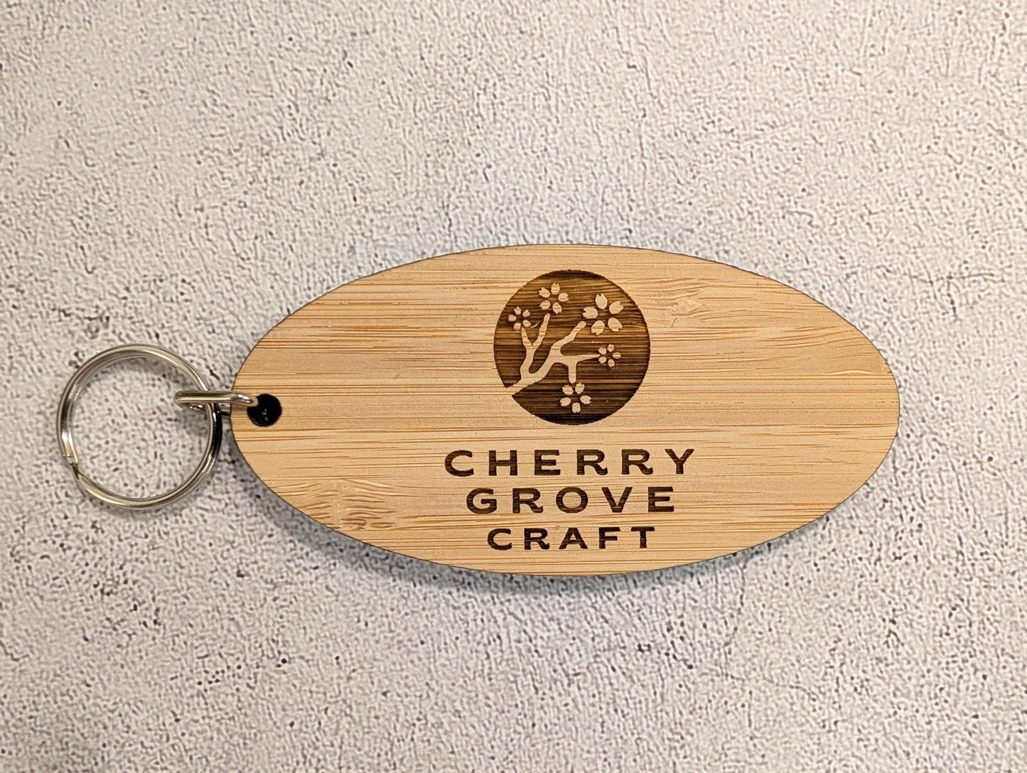 5mm bamboo oval business keyring engraved with Cherry Grove Craft logo and cherry blossom branch, metal split ring