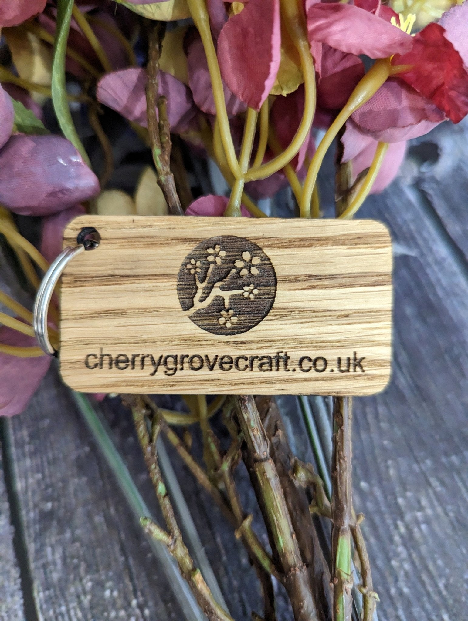 Double-sided 65x35mm keyring close-up — engraved logo on oak