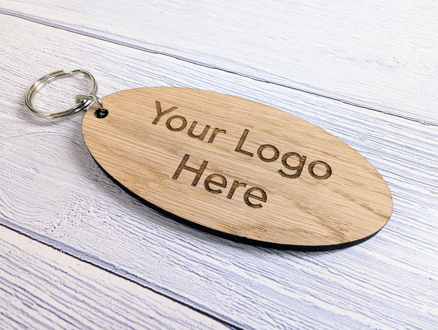 Large oval oak keyring close-up — 100x50mm, logo engraved, split ring