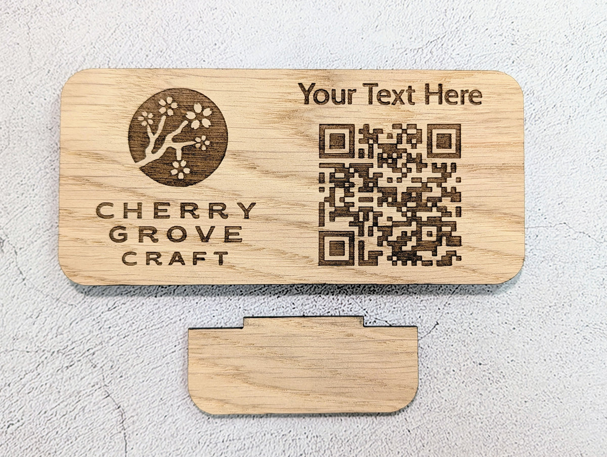 Custom QR code stand laid flat above its separate tab stand, engraved with a logo, text line and QR code
