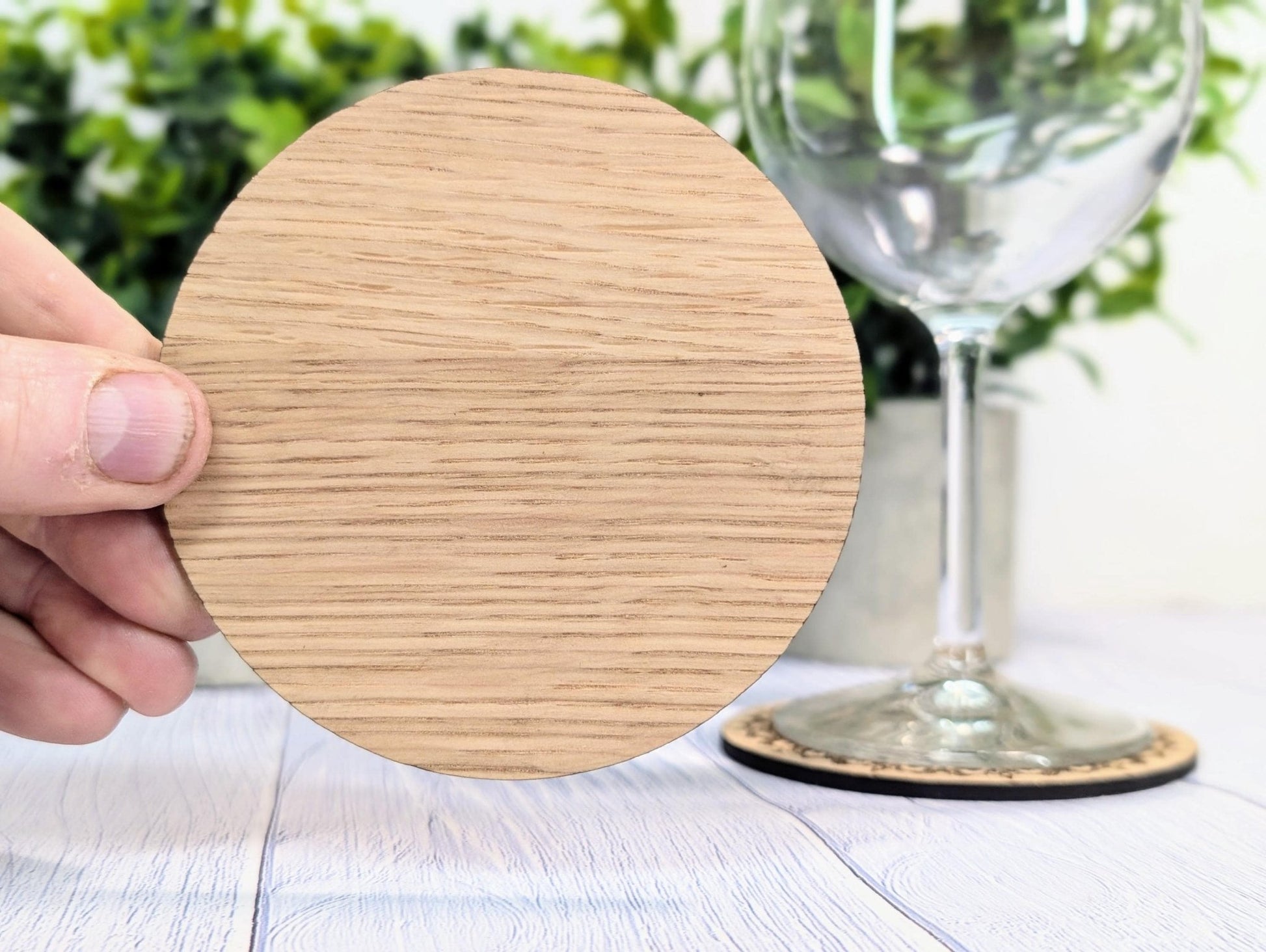 Engraved border coaster from above — 100mm, natural oak grain