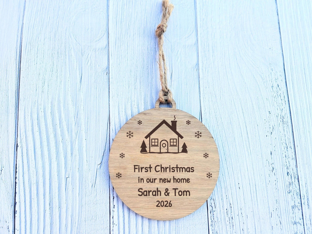 First Christmas in our new home oak bauble engraved with a house, snowflakes, names and year, 100mm, with jute loop