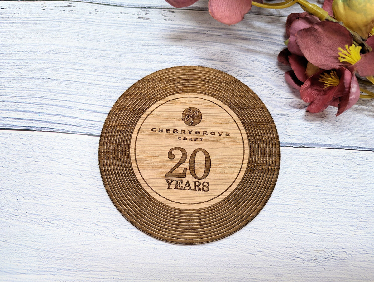 Branded vinyl record coaster for businesses with logo and milestone, oak