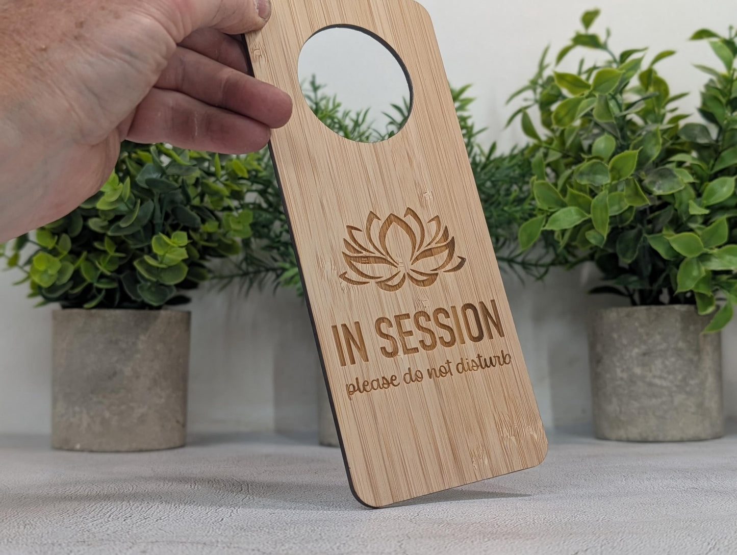 In Session bamboo door hanger hanging on door handle — lotus motif, single-sided, indoor use