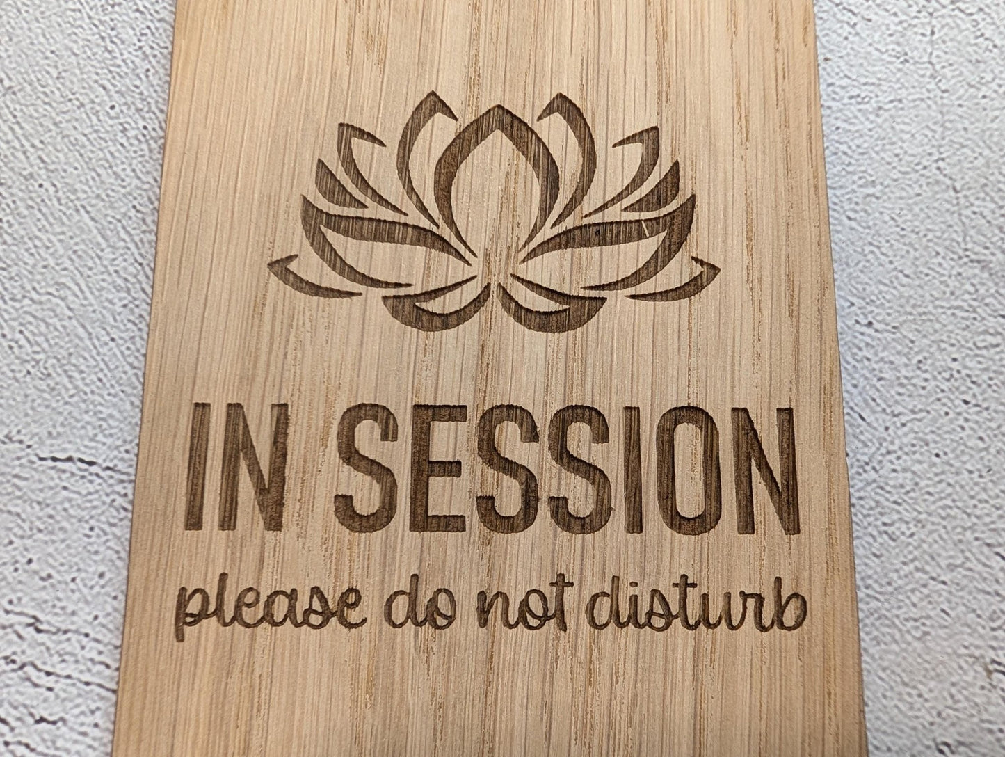 In Session oak and bamboo door hangers side by side showing grain comparison — lotus design