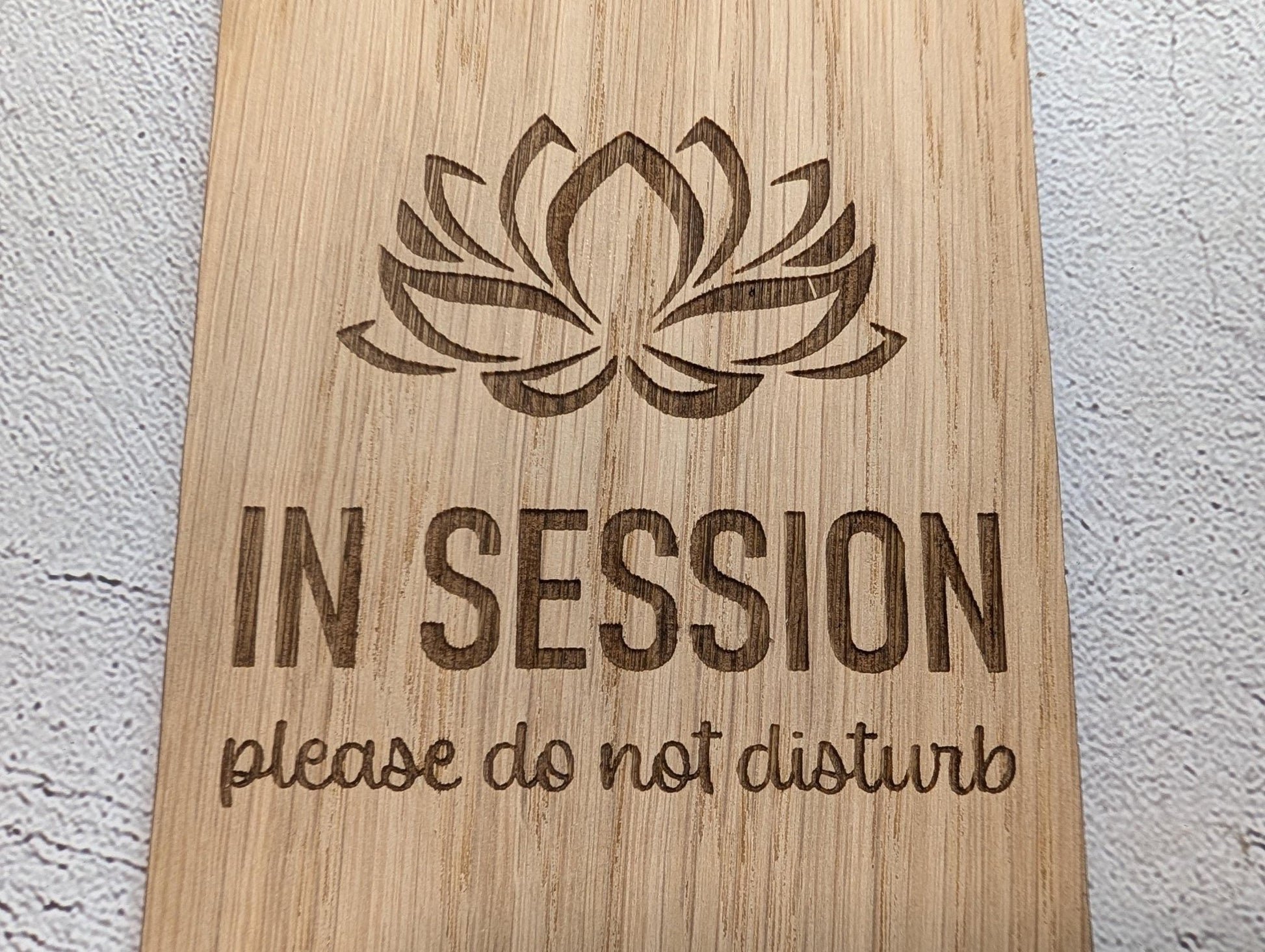 In Session oak and bamboo door hangers side by side showing grain comparison — lotus design
