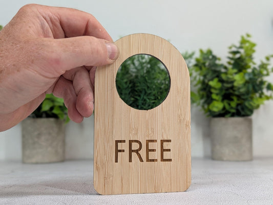In Use / Free door hanger in 5mm FSC-certified bamboo, 89x144mm, hanging on a door handle