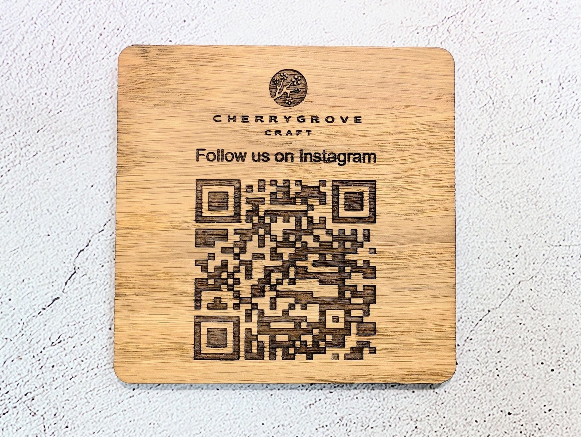 Close-up of laser engraved QR code on oak coaster — permanent engraving, Danish oiled