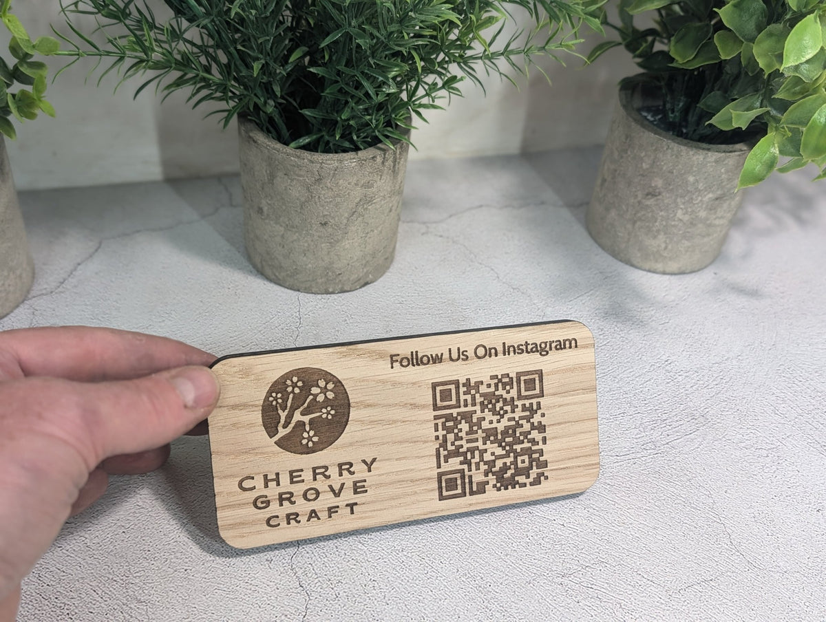 Hand holding the oak Instagram QR code stand in front of potted plants