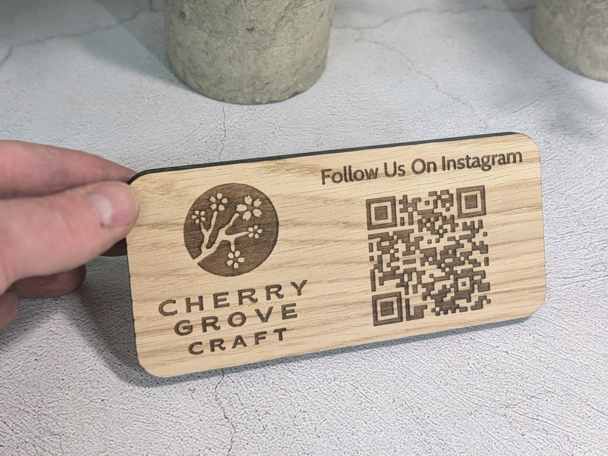 Hand holding the 150 × 70mm oak Instagram QR code stand to show its size