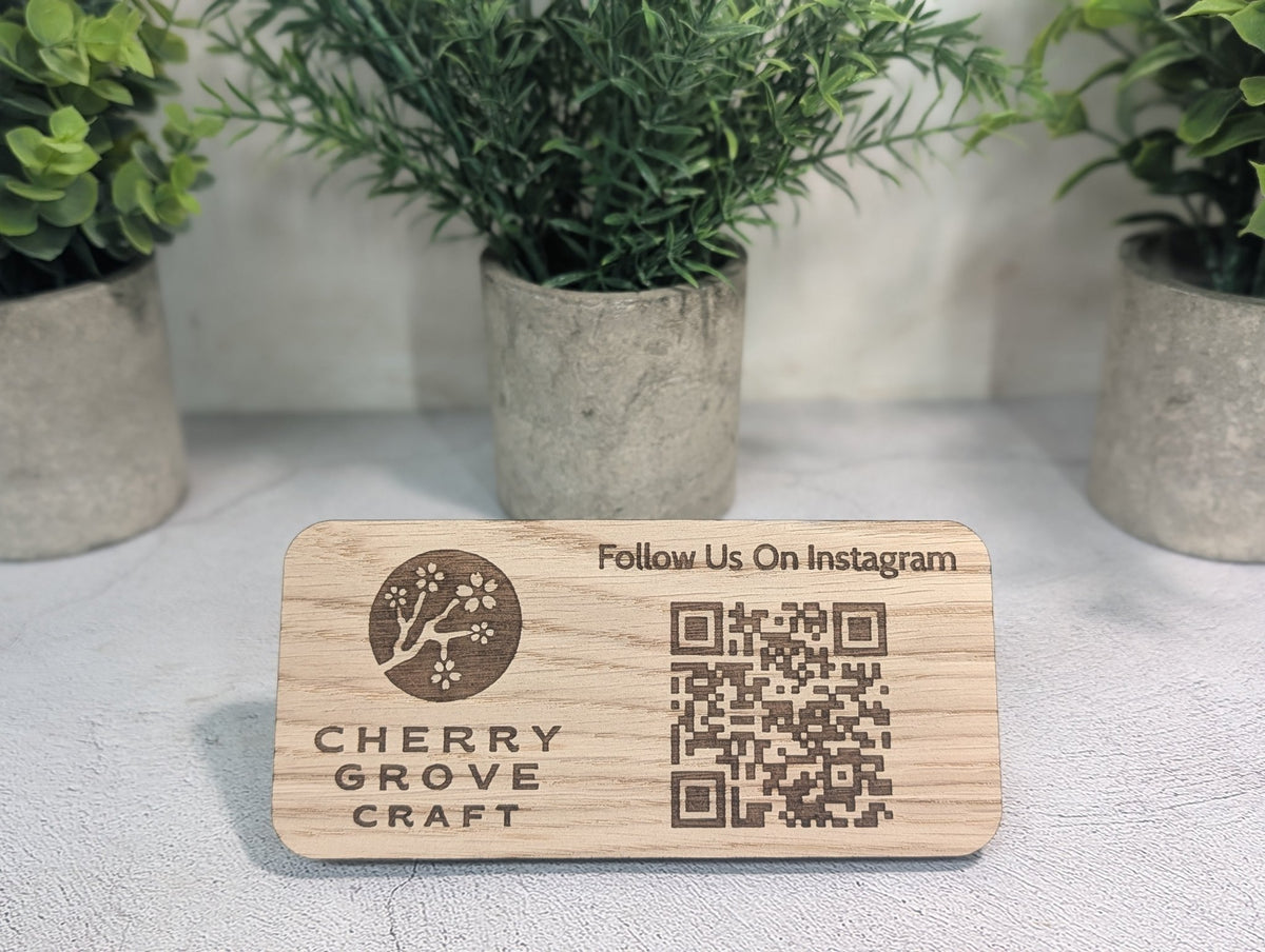 Oak Instagram QR code stand standing on a table in front of three potted plants