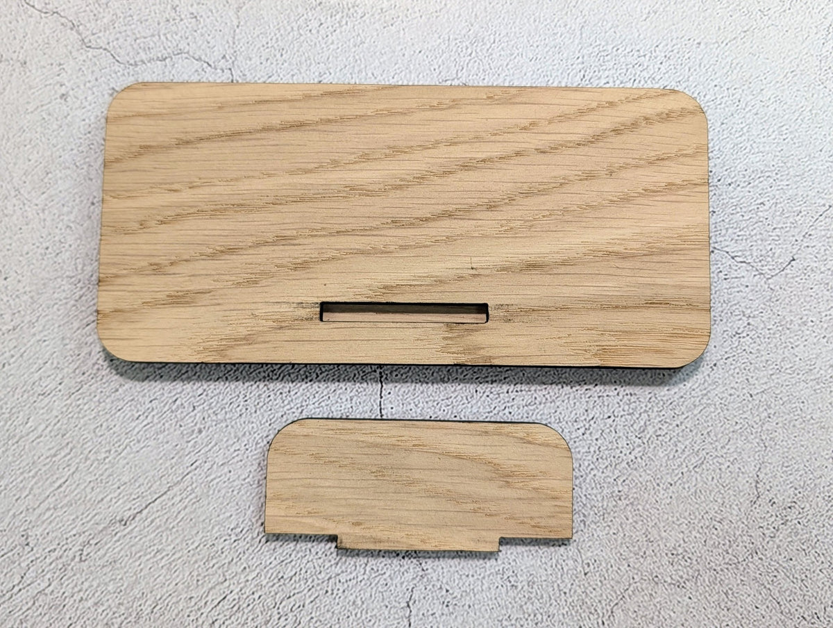 Unassembled stand: back of the oak panel with its slot, and the separate tab that pushes into it