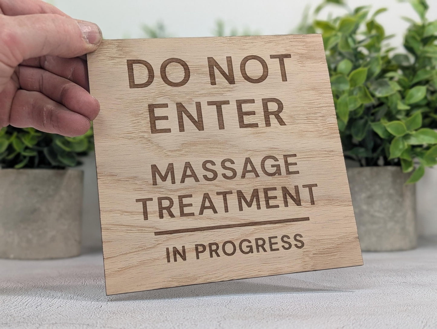 Massage treatment sign detail showing laser-engraved text on oak veneered MDF surface