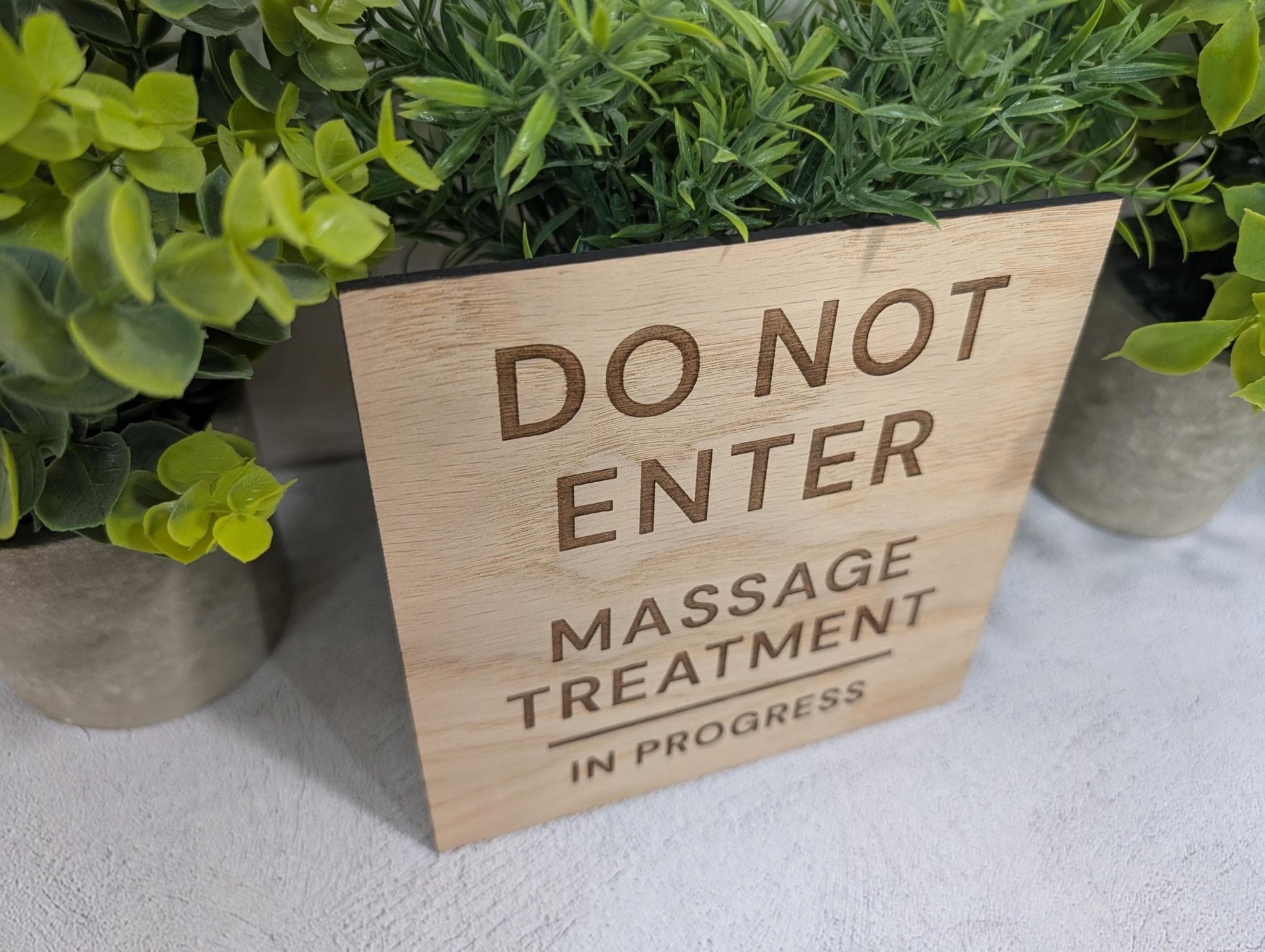 Massage in progress oak sign mounted on white door — clean natural finish, therapy room setting