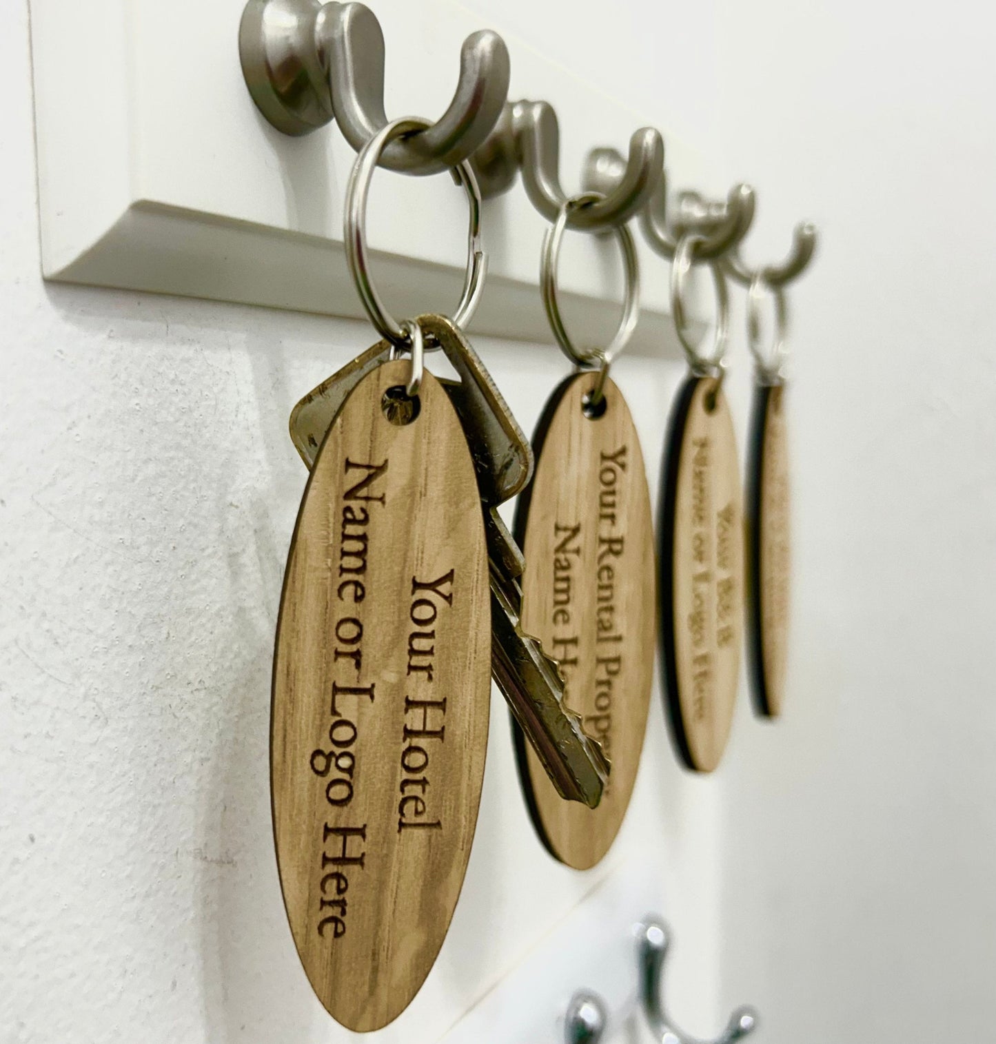 Double-sided oval keyring close-up — logo front, text reverse, oak