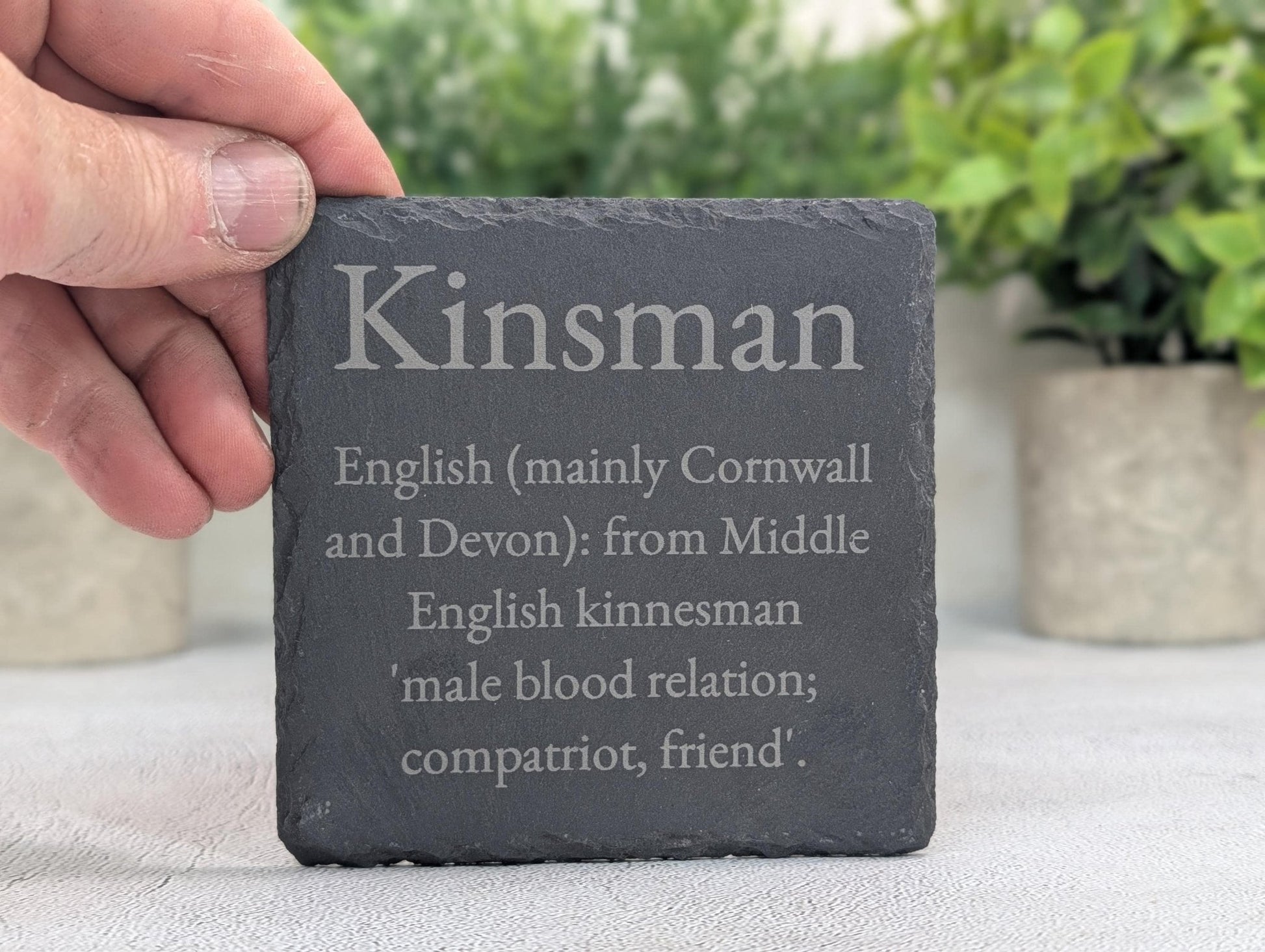 Surname coaster on table showing engraved name and etymology text