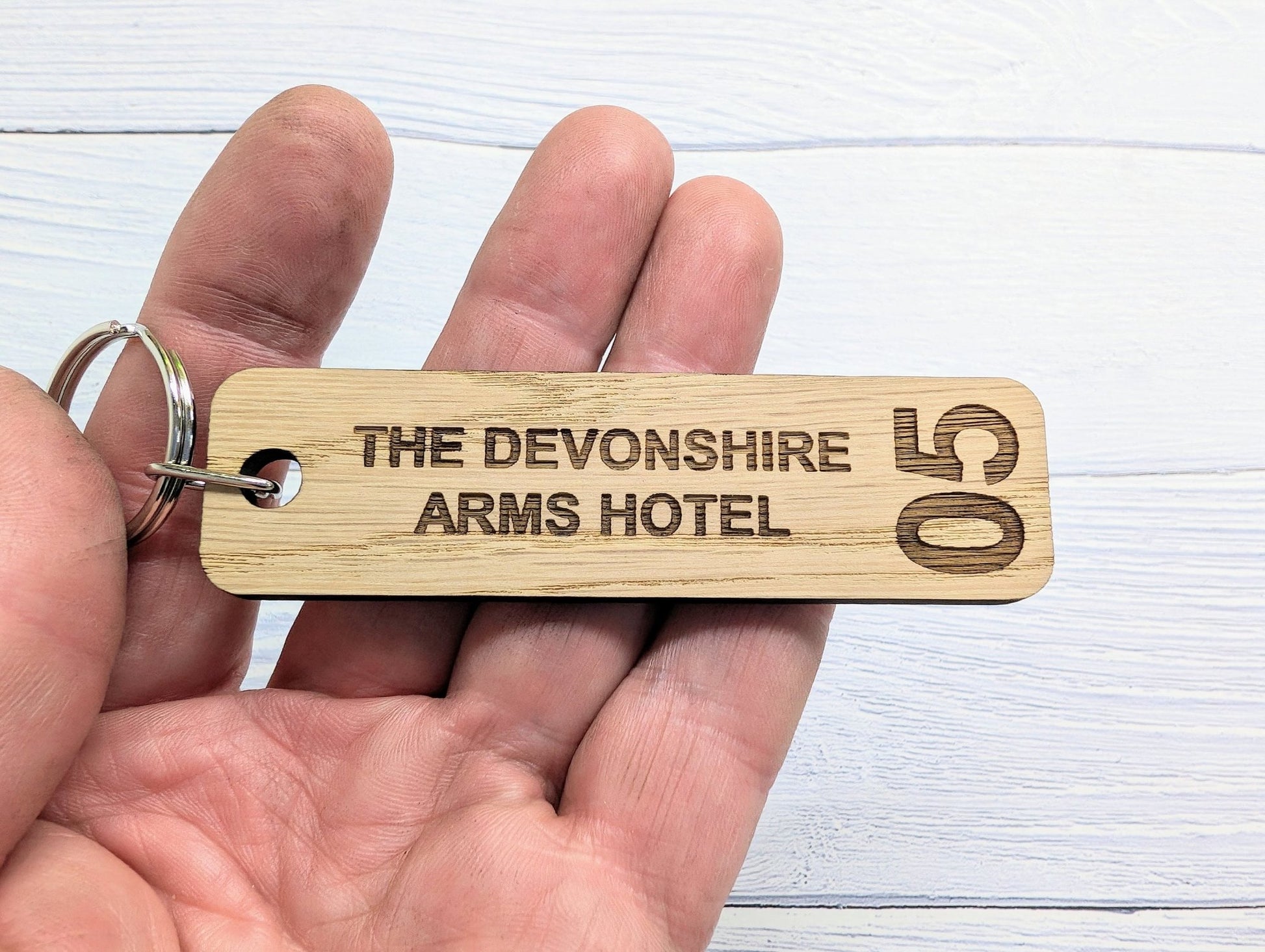 Hotel room keyring close-up — 90x25mm oak, room number and hotel name