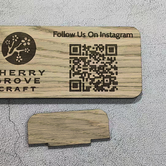 Short video of the tab stand being pushed into the slot on the back of the oak Instagram QR code stand