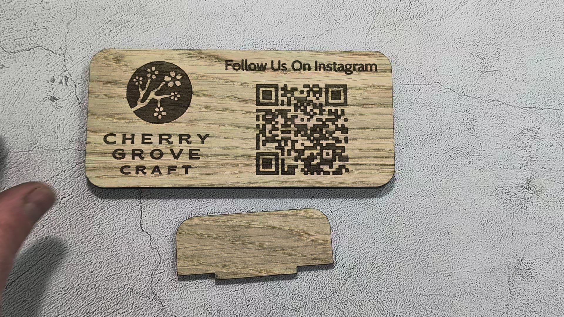 Short video of the tab stand being pushed into the slot on the back of the oak Instagram QR code stand