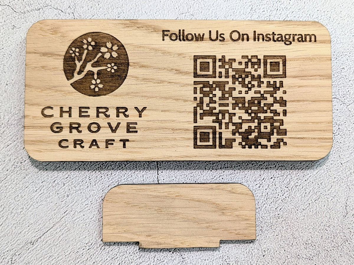 Oak QR code stand engraved with a logo, "Follow Us On Instagram" and a QR code, laid flat above its tab stand